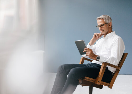 Manager sitting in office, using digital tablet