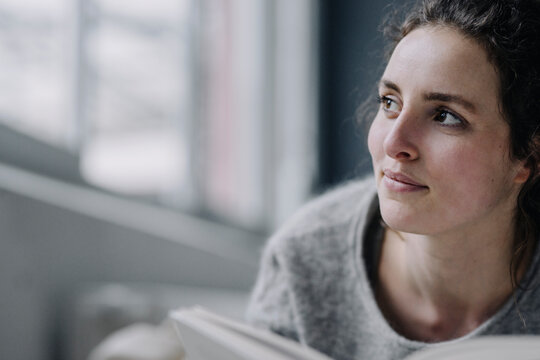 Portrait of relaxed young woman with book at home