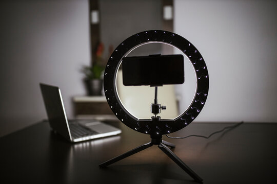 Smart phone with LED ring light and laptop on table
