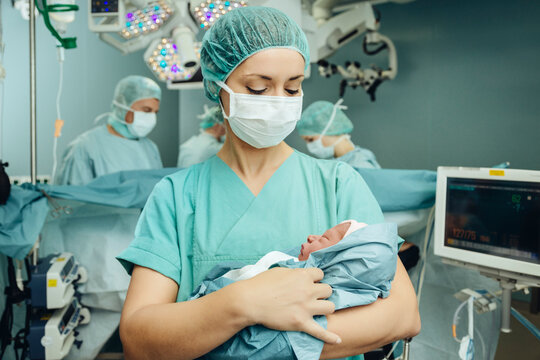 Operating room nurse holding newborn in operating room