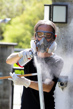 Person spray painting outdoors with safety mask and goggles