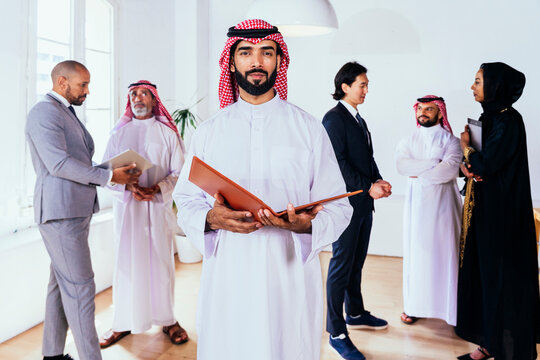 Saudi business leader holding folder at international office meeting