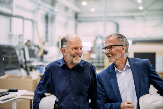 Two senior men in a factory discussing development and planning
