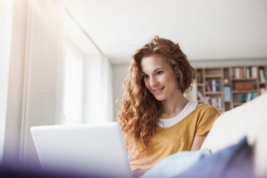 Woman at home sitting on couch using laptop