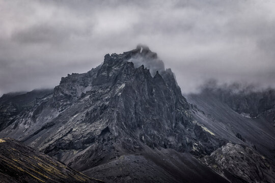 Dark jagged volcanic peak emerges from thick mist in Iceland