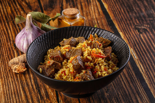 Asian traditional pilaf with beef, garlic, and spices on rustic wood