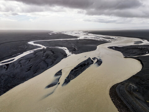 Aerial view of glacial meltwater carving black sand in Iceland