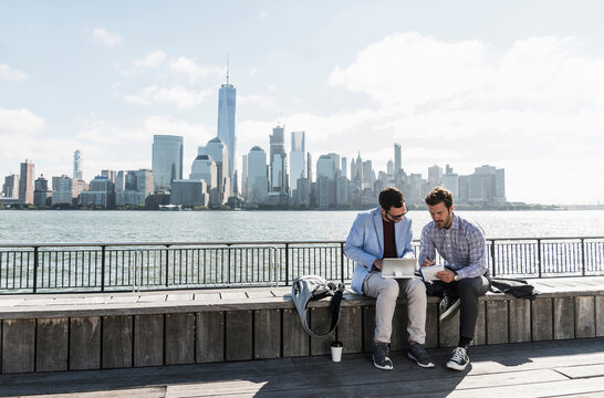USA, two businessmen working at New Jersey waterfront with view to Manhattan