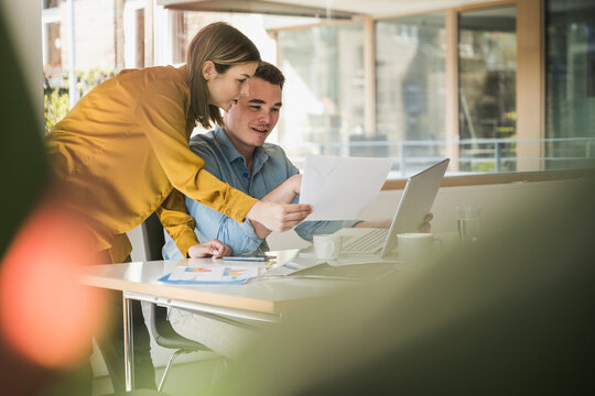 Businesswoman and businessman with laptop and documents at desk in office