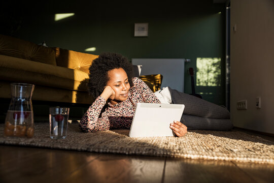 Woman relaxing on floor at home using tablet