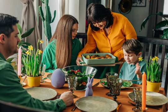 Grandmother serving food to grandchildren at Easter dinner