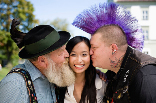 Bavarian and punk kissing smiling person on cheek in beer garden