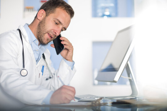 Doctor at desk talking on cell phone