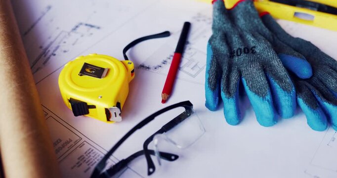 Gloves, architecture and blueprint on table with safety documents, construction or building design. Floor plan, paperwork and glasses for ppe, equipment and tools for infrastructure development