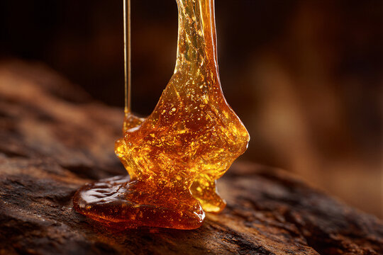 Macro shot of golden maple taffy pulled into glossy amber strands, lit by warm cinematic light over blurred wood. Clean negative space ideal for gourmet magazines, bakery ads, and culinary branding.