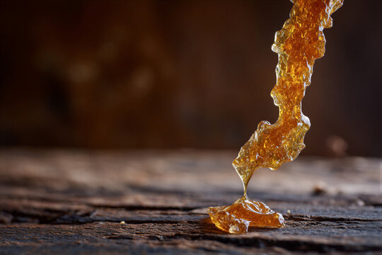 Macro shot of golden maple taffy pulled into glossy amber strands, lit by warm cinematic light over blurred wood. Clean negative space ideal for gourmet magazines, bakery ads, and culinary branding.