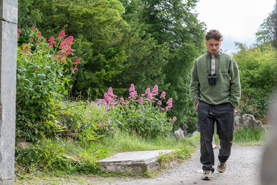 Young man walking through overgrown cemetery path