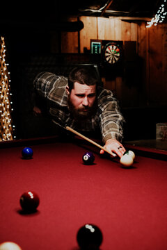 Focused man with beard lining up a pool shot
