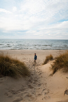 Man looking back while walking on a sandy beach path
