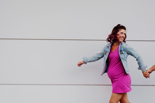 Joyful pregnant woman holding hands and walking