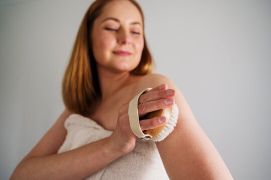 Woman dry brushing body brush, skincare wellness, self care routine