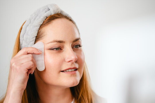 Woman using gua sha for facial massage, skin care beauty