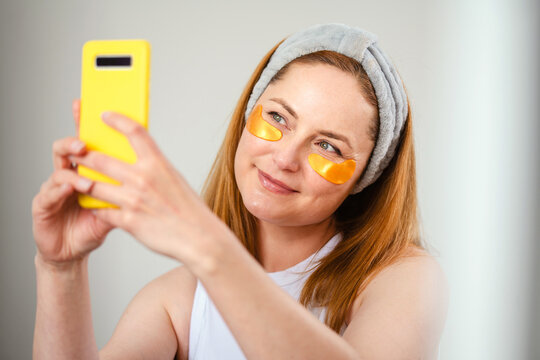 Woman with eye patches taking selfie, beauty routine