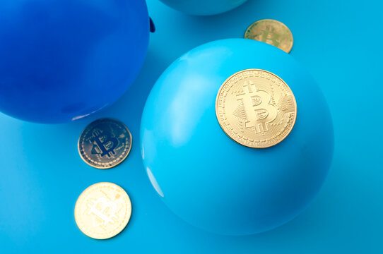Golden Bitcoin coins resting on blue balloons against a blue background, a conceptual image of the cryptocurrency bubble. Crypto market volatility, investment risk and digital finance concept