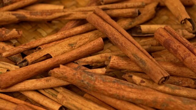 Panning tracking shot over a macro texture pile of cinnamon sticks on woven mat