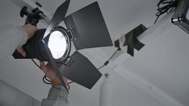 Low Angle View of Gaffer Hands Adjusting Professional Studio Light on Ceiling Grid