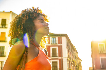 Naklejka premium Young woman enjoying sunshine in city street