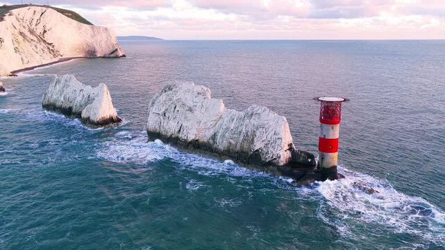4K drone panorama of The Needles chalk stacks and historic lighthouse at sunset on a summer evening off the Isle of Wight, England.