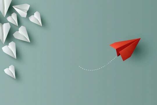 Red paper plane veering away from white planes on muted surface