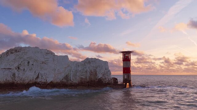 4K drone panorama of The Needles chalk stacks and historic lighthouse at sunset on a summer evening off the Isle of Wight, England.