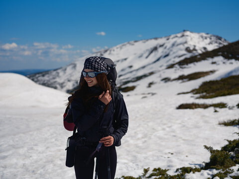 Smiling hiker with backpack standing on snowy slope in Carpathians