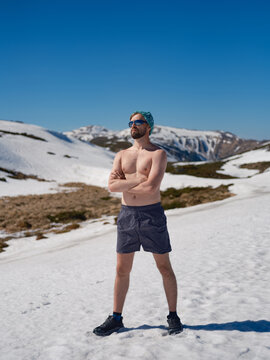 Shirtless man practicing hardening on snowy slope in Carpathians