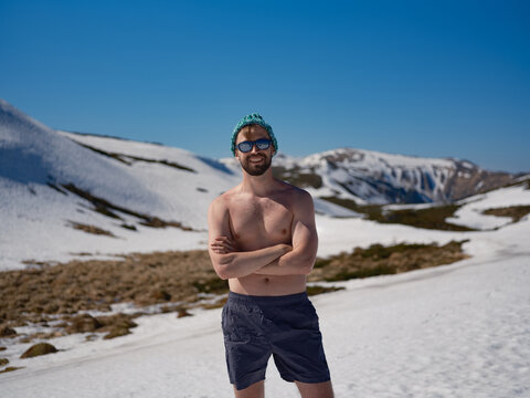 Smiling shirtless man practicing hardening on snowy slope in Carpathians