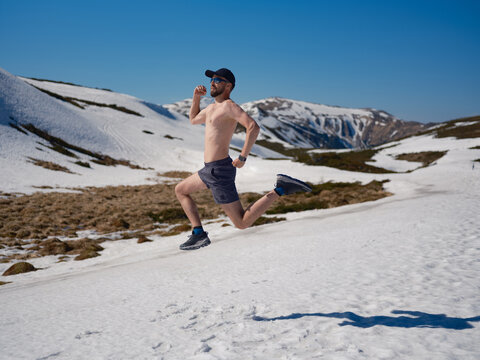 Active shirtless man running on snowy slope in Carpathians