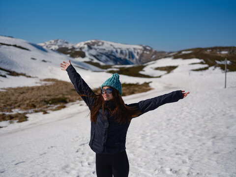 Happy woman with arms outstretched on snowy mountain slope in Carpathians