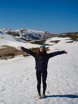 Happy woman with arms outstretched on snowy mountain slope in Carpathians