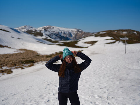 Smiling woman wearing beanie on snowy mountain slope in Carpathians