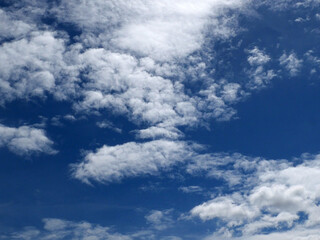 Fototapeta premium A bright blue sky background with beautiful clouds; a bottom-down, wide-angle view.