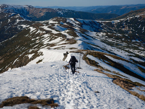 Hiker trekking along snow-covered mountain path in Carpathians