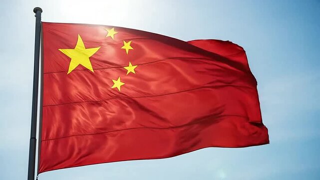 A bright red flag with yellow stars waving against a clear blue sky background