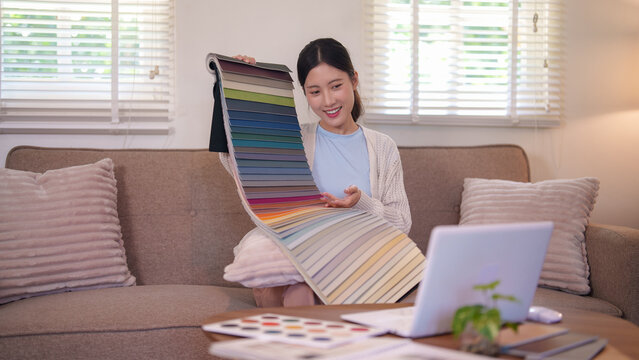 Asian woman interior designer showing color palette swatches for furniture project at home