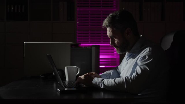 Night office failure worries businessman. Night office concentration on computer screen. Night office worker feeling sad and tired. Night office corporate job causes stress.