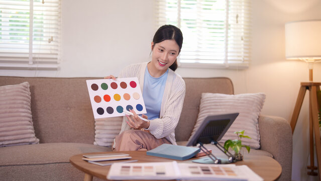 Asian woman designer presenting color palette samples for furniture design project at home
