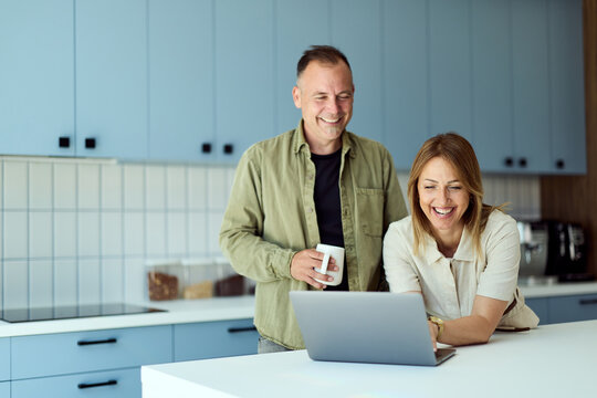 Smiling Couple Working Together On Laptop In Modern Home Kitchen&mdash;Remote Work, Family, Collaboration And Lifestyle