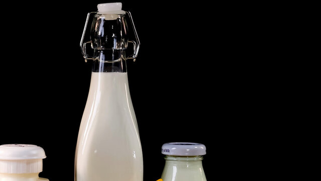 Glass Milk Bottles and Jars Against a Solid Black Background