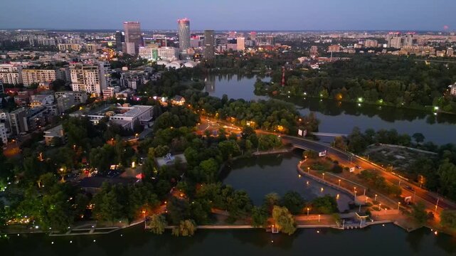 Nighttime aerial drone perspective of Bucharest cityscape, showing Herastrau park surroundings and the glowing modern office buildings in Pipera financial center, Romania.